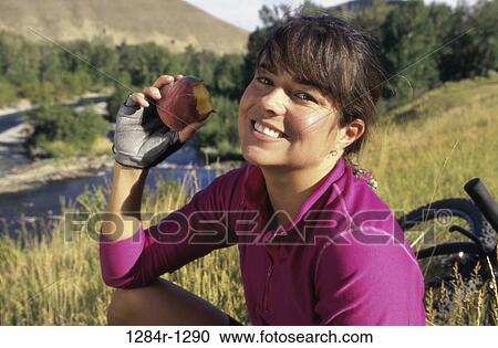 Stock Image - Portrait of a woman eating an apple. Fotosearch