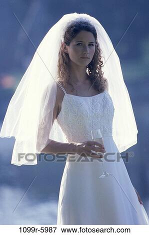 Stock Photo - Portrait of a young bride holding a glass of wine. Fotosearch