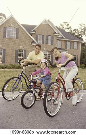 Stock Image - Portrait of a young couple cycling with their daughter. Fotosearch