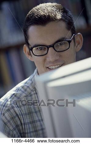 Portrait of a young man sitting in front of a computer monitor View Large Photo Image Stock Photograph - Portrait of a young man sitting in front of a computer monitor. Fotosearch