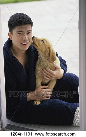 Stock Image - Portrait of a young man sitting with a dog. Fotosearch