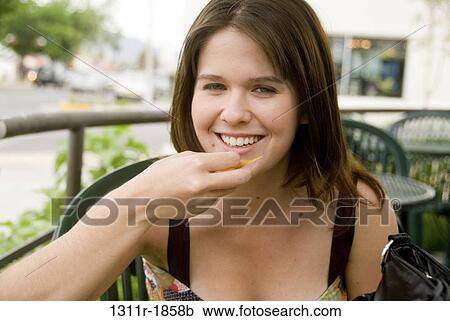 Stock Image - Portrait of a young woman eating food. Fotosearch