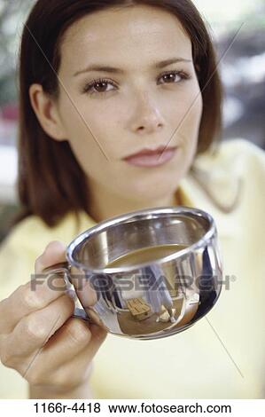 Stock Photo - Portrait of a young woman holding out a teacup. Fotosearch