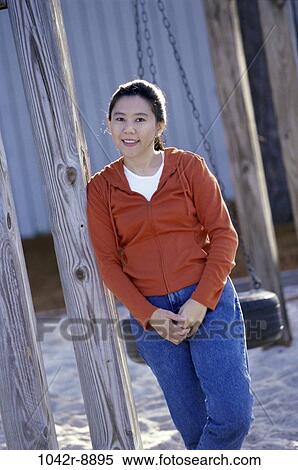 Portrait of a young woman leaning against a wooden post View Large Photo Image Stock Photography - Portrait of a young woman leaning against a wooden post. Fotosearch