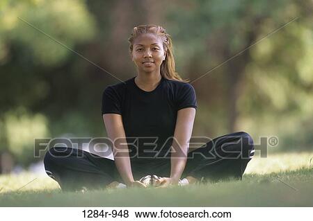 Stock Photo - Portrait of a young woman meditating on a lawn. Fotosearch