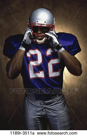 Stock Image - Portrait of an American football player removing his helmet. Fotosearch