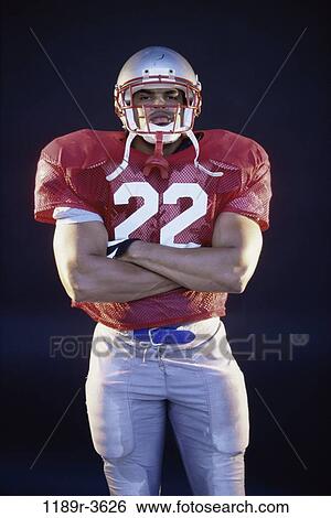 Stock Photograph - Portrait of an American football player standing with his arms folded. Fotosearch
