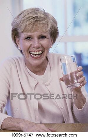 Portrait of an elderly woman holding a glass of water View Large Photo Image Stock Photo - Portrait of an elderly woman holding a glass of water. Fotosearch