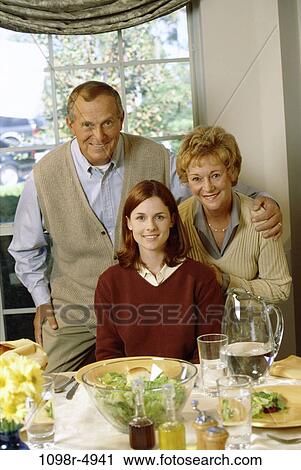 Stock Image - Portrait of parents and their daughter at a dining table. Fotosearch