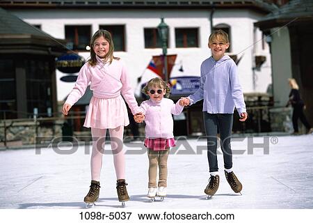Stock Photo - Portrait of three children holding hands ice skating. Fotosearch