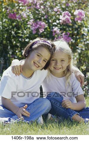 Portrait of two girls sitting on a lawn View Large Photo Image Stock Image - Portrait of two girls sitting on a lawn. Fotosearch