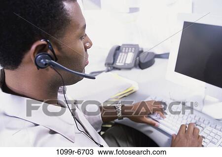 Stock Image - Rear view of a customer service representative working on a computer. Fotosearch