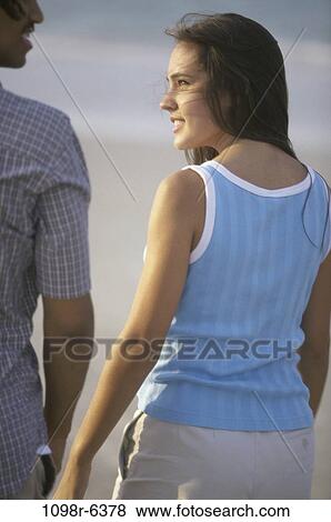 Rear view of a teenage couple walking on the beach View Large Photo Image Stock Photo - Rear view of a teenage couple walking on the beach. Fotosearch