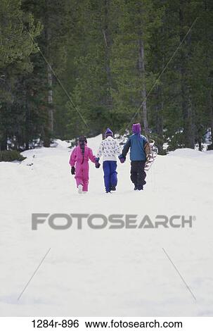 Rear view of two boys and a girl walking in snow View Large Photo Image Stock Photograph - Rear view of two boys and a girl walking in snow. Fotosearch