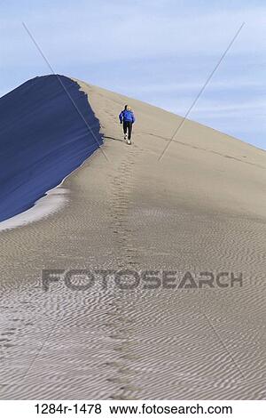Rear view of woman running up a sand dune View Large Photo Image Stock Photo - Rear view of woman running up a sand dune. Fotosearch