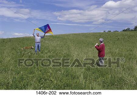 Senior couple flying a kite in a field View Large Photo Image Stock Image - Senior couple flying a kite in a field. Fotosearch