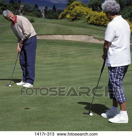 Stock Image - Senior couple playing golf. Fotosearch