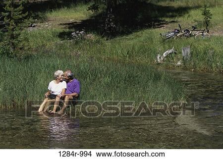 Senior couple sitting on a riverbank View Large Photo Image Picture - Senior couple sitting on a riverbank. Fotosearch