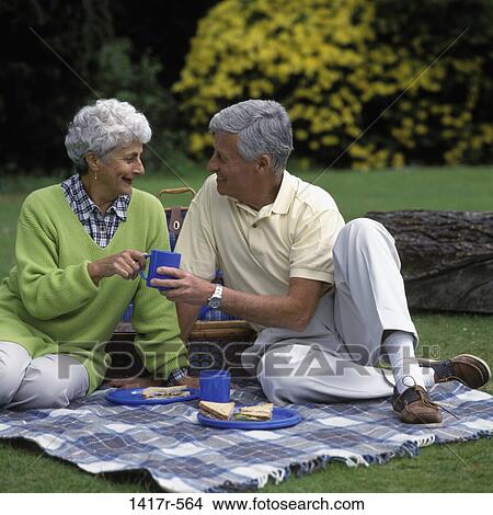 Senior couple sitting together outdoors at a picnic View Large Photo Image Picture - Senior couple sitting together outdoors at a picnic. Fotosearch