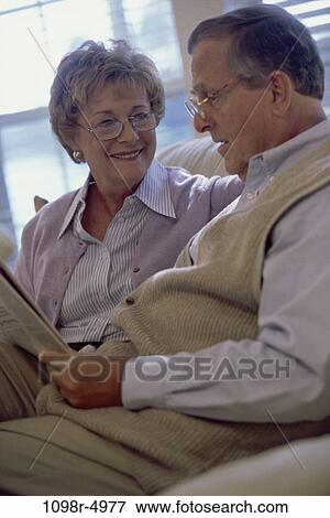 Senior couple sitting together reading a newspaper View Large Photo Image Stock Photo - Senior couple sitting together reading a newspaper. Fotosearch