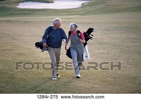 Senior couple walking on a golf course carrying golf bags View Large Photo Image Stock Photography - Senior couple walking on a golf course carrying golf bags. Fotosearch