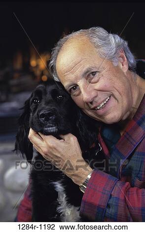 Stock Image - Senior man holding a dog. Fotosearch