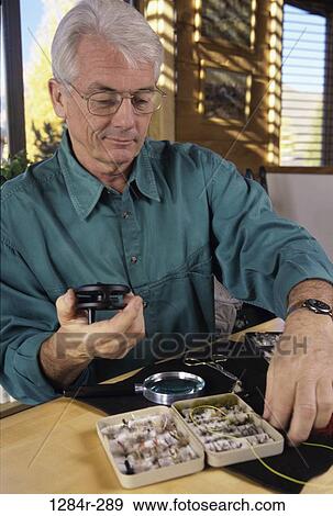 Stock Photo - Senior man holding a fishing reel. Fotosearch