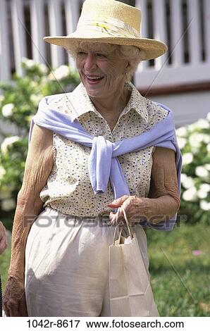 Senior woman carrying a shopping bag smiling View Large Photo Image Stock Photo - Senior woman carrying a shopping bag smiling. Fotosearch