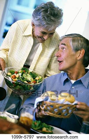 Stock Photo - Senior woman holding a bowl of salad looking at a senior man. Fotosearch