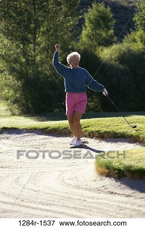 Senior woman holding a golf club View Large Photo Image Stock Photo - Senior woman holding a golf club. Fotosearch