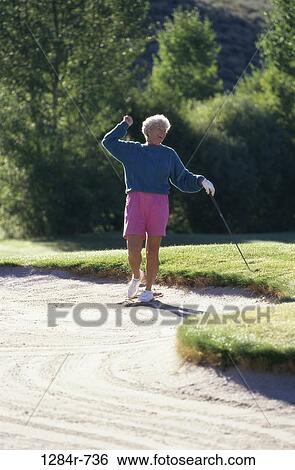 Senior woman holding a golf club View Large Photo Image Stock Photograph - Senior woman holding a golf club. Fotosearch