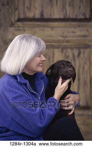 Stock Image - Senior woman holding her dog. Fotosearch