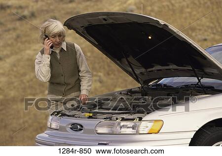 Senior woman standing near a broken down car talking on a mobile phone View Large Photo Image Stock Image - Senior woman standing near a broken down car talking on a mobile phone. Fotosearch