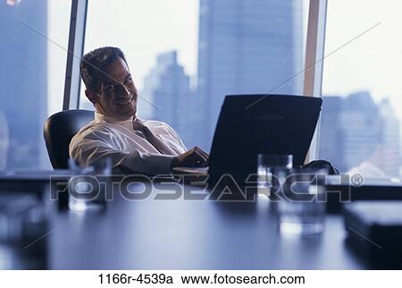 Stock Image - Side profile of a businessman smiling while working on a laptop. Fotosearch