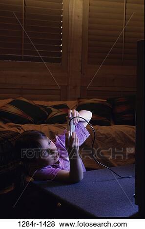 Stock Photo - Side profile of a girl operating a game joystick. Fotosearch