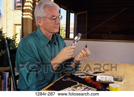 Side profile of a senior man looking through a magnifying glass at a fishing lure View Large Photo Image Stock Photo - Side profile of a senior man looking through a magnifying glass at a fishing lure. Fotosearch