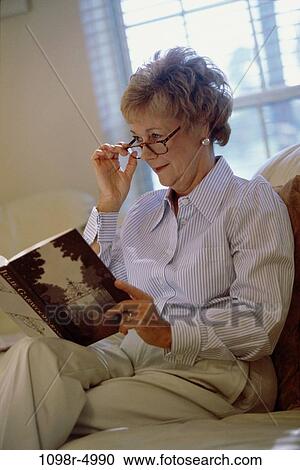 Side profile of a woman sitting on a couch reading a book View Large Photo Image Stock Image - Side profile of a woman sitting on a couch reading a book. Fotosearch