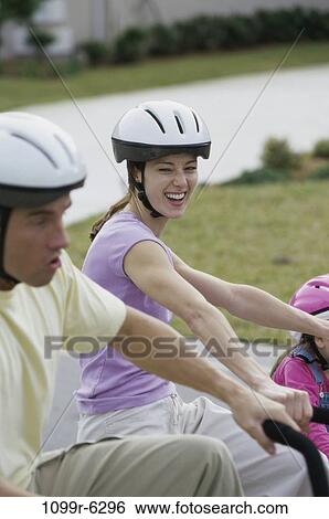 Stock Photograph - Side profile of a young couple cycling. Fotosearch