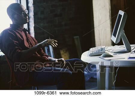 Side profile of a young man sitting in front of a computer View Large Photo Image Stock Image - Side profile of a young man sitting in front of a computer. Fotosearch