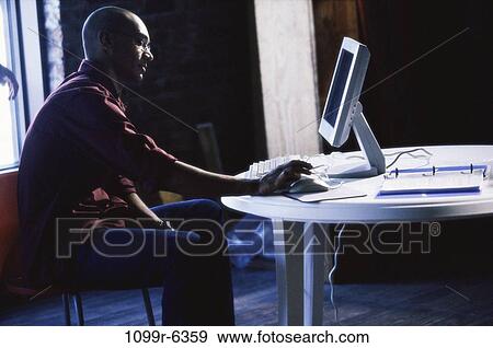 Side profile of a young man sitting using a computer View Large Photo Image Stock Photo - Side profile of a young man sitting using a computer. Fotosearch