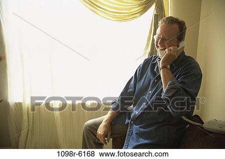 Stock Photo - Side profile of mature man talking on a telephone. Fotosearch
