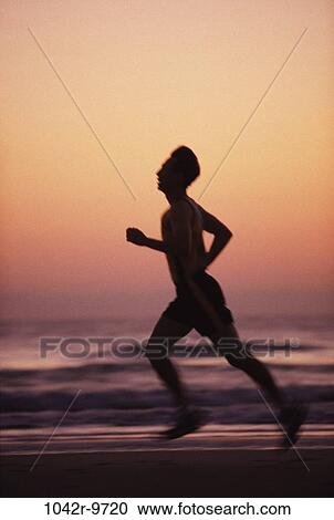 Stock Image - Silhouette of a man running on the beach. Fotosearch