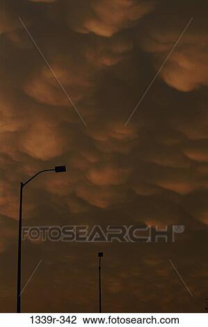 Silhouette of a streetlight against a cloudy sky View Large Photo Image Stock Image - Silhouette of a streetlight against a cloudy sky. Fotosearch