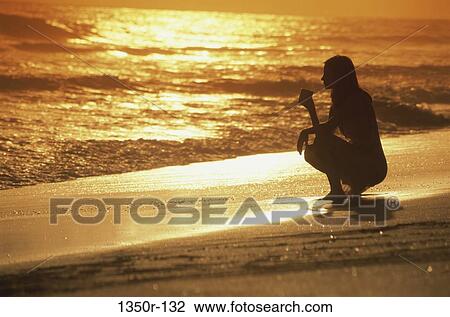 Silhouette of a young woman squatting on the beach during sunset View Large Photo Image Stock Image - Silhouette of a young woman squatting on the beach during sunset. Fotosearch