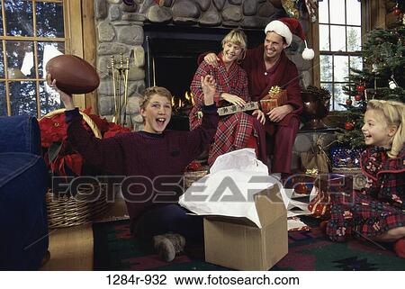 Stock Image - Son holding a rugby ball while his parents watch. Fotosearch