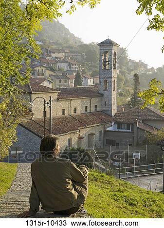 Switzerland, Ticino, Lugano, Bre, Man sitting on grassy hill overlooking town View Large Photo Image Stock Image - Switzerland, Ticino, Lugano, Bre, Man sitting on grassy hill overlooking town. Fotosearch