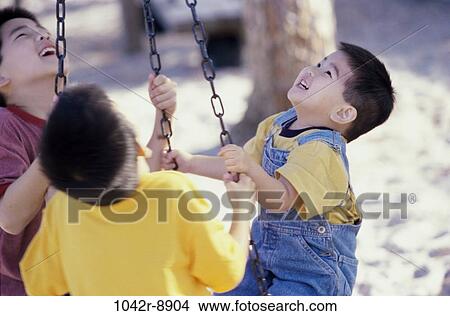 Three boys playing on a swing View Large Photo Image Picture - Three boys playing on a swing. Fotosearch
