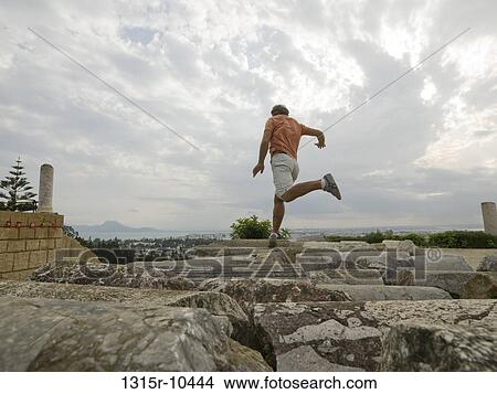 Tunisia, Carthage, Man jumping between fallen columns at Carthage ruin View Large Photo Image Picture - Tunisia, Carthage, Man jumping between fallen columns at Carthage ruin. Fotosearch