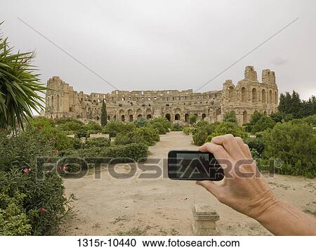 Tunisia, El Djem, Woman's hand taking picture of distant coliseum with cell phone View Large Photo Image Stock Image - Tunisia, El Djem, Woman's hand taking picture of distant coliseum with cell phone. Fotosearch