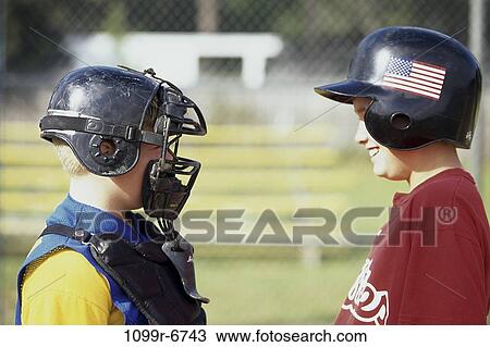 Stock Image - Two boys in baseball uniforms looking at each other. Fotosearch